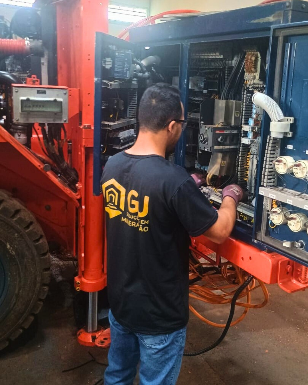 Técnico da GJ Soluções realizando manutenção em painel eletro-hidráulico de equipamento pesado